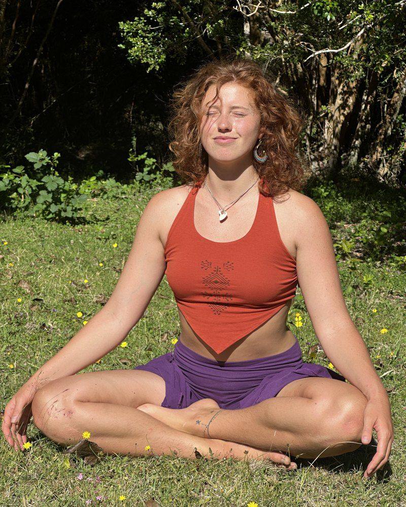 Jazmin sitting cross-legged on the grass, eyes closed