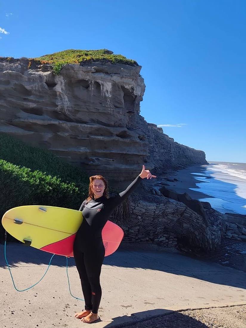 Jazmin with her surfboard by the sea