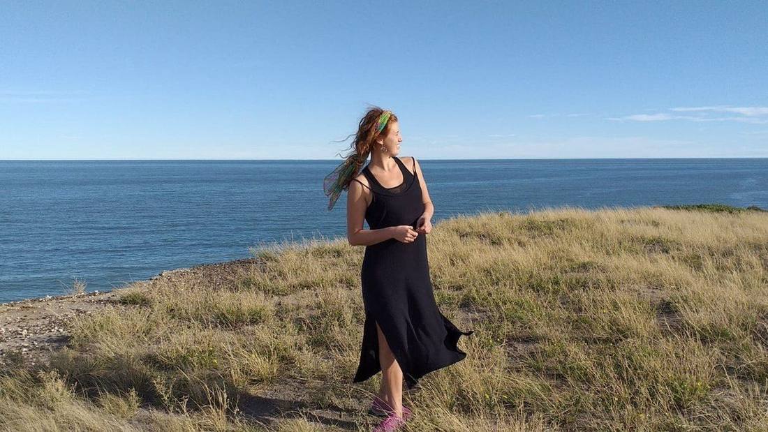 Jazmin walking along a grassy headland above the sea