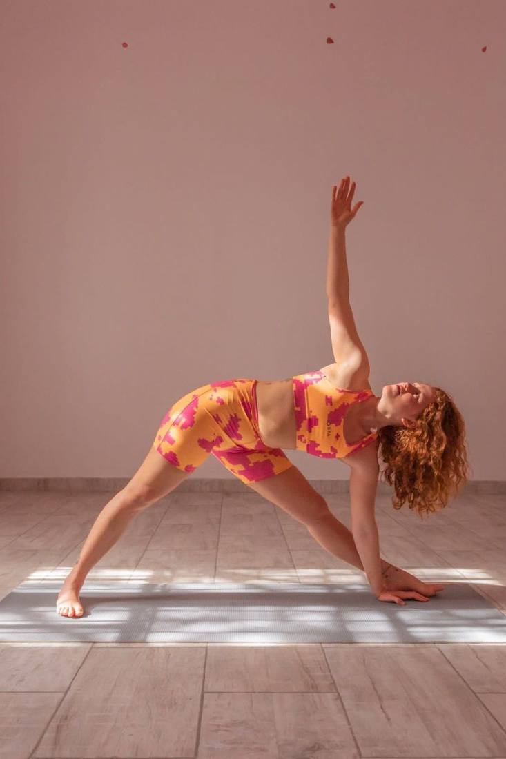Jazmin in a triangle pose in soft window light